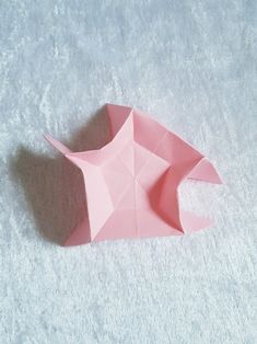 a pink origami fish sitting on top of a white surface