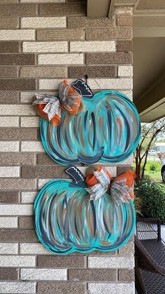 two glass pumpkins are hanging on the side of a brick building with ribbon tied around them