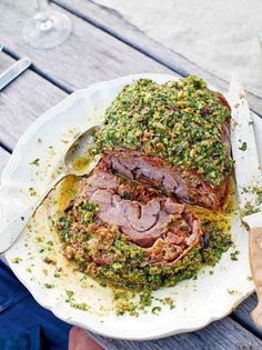 a white plate topped with meat covered in pesto and sauce next to a fork