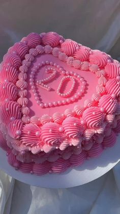 a pink heart shaped cake sitting on top of a white tablecloth covered table cloth