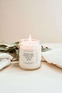 a candle sitting on top of a table next to some white towels and eucalyptus leaves