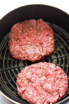 two hamburger patties cooking in an air fryer