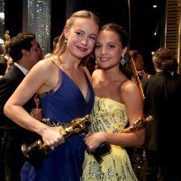 two women standing next to each other holding oscars trophies and posing for the camera