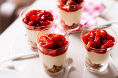 four small desserts with strawberries in them on a table