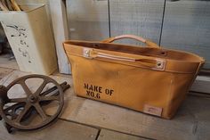 a brown bag sitting on top of a wooden floor next to an old metal wheel