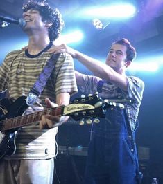 two young men singing into microphones while playing guitar