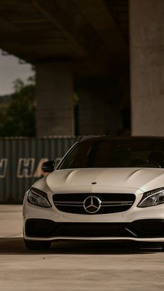 the front end of a white car parked under a bridge