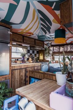 a kitchen area with a table, refrigerator and potted plants