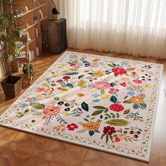 a white rug with colorful flowers on it in front of a window and potted plant