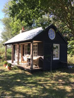 a small black cabin sitting in the grass