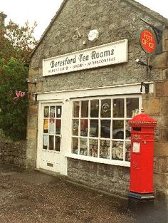 an old stone building with a red post box in front