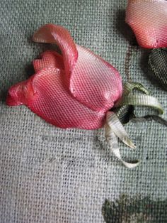 two pink flowers sitting on top of a gray cloth covered tablecloth next to each other