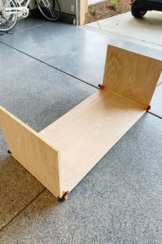 a wooden bench sitting on top of a cement floor next to a bike rack and bicycle