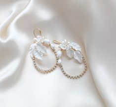 Introducing our stunning CELENA hoop earrings, perfect for weddings or any special occasion. Handcrafted with delicate white opal crystals and elegant freshwater pearls and flowers, these earrings add a touch of glamor and sophistication to any outfit. Make a statement with our gold floral hoops! - Handcrafted in my PA studio with genuine white opal Austrian crystals- Freshwater pearls- Polymer clay flowers and leaves- Yellow gold finish is pictured. Available in rose gold, yellow gold or rhodium (silver)- Earrings measure 2.5 inches x 1.5 inch- Handcrafted in the US.- Nickel free and hypoallergenic- PLEASE ALLOW APPROX 10 BUSINESS DAYS FOR COMPLETION BEFORE SHIPPING.This is an original design by © Treasures by Agnes