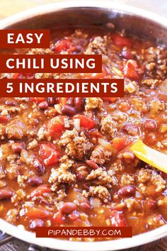 a pot filled with chili and meat next to a wooden table