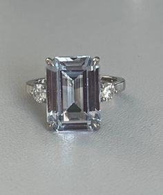 White gold (18k) ring adorned with an emerald-cut aquamarine of approximately 7.91 ct (13 x 9 mm) supported on each side by a round brilliant-cut diamond of approximately 0.17 ct each. Gross Weight: 5.95 g. Size: 51.5 Possibility of sizing, contact us. Further information : We issue an invoice as well as a certificate of authenticity established by our qualified gemologist (LFG Paris). Our photos are not reworked and are taken in a natural light environment. We can send you a short video upon si White Blue Topaz Rings For Formal Occasions, Formal White Blue Topaz Ring, Formal Baguette Cut Diamond Topaz Ring, Emerald Cut Diamond Topaz Ring For Formal Occasions, Formal Aquamarine Diamond Ring With Prong Setting, Elegant White Gold Octagon Topaz Ring, Formal Aquamarine Diamond Ring With Brilliant Cut, Formal Blue Topaz Diamond Ring In Diamond White, Aquamarine Brilliant Cut Diamond Ring For Formal Occasions