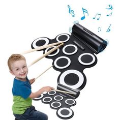 a young boy playing with musical instruments on top of a drum pad and drumsticks