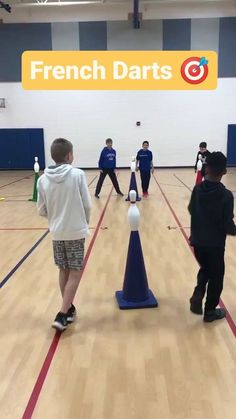 several young boys are practicing in an indoor gym with cones and balls on the floor