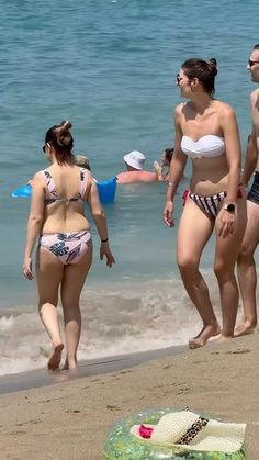 three women in bikinis walking on the beach