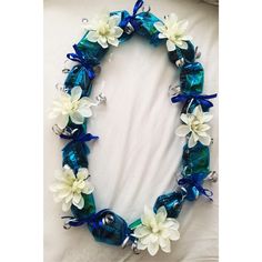 a blue and white flowered necklace with bells on the bottom is laying on a bed