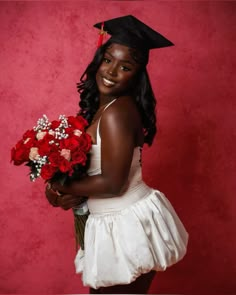 a woman in a graduation cap and gown holding red roses with her hand on her hip