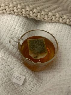 a cup of tea with some sort of fish in it on a white blanket next to a tag