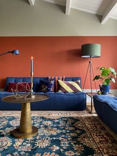 a living room with blue couches and orange walls