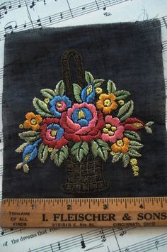 a piece of cloth with flowers on it next to a ruler and sheet of music