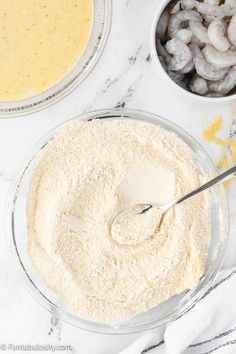 the ingredients to make shrimp and grits in bowls on a white marble counter top