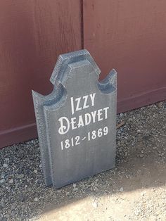 a tombstone sitting in front of a red door with the name lizy deadyet on it