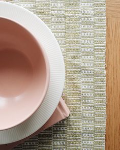 two white plates and a pink bowl sitting on top of a wooden table next to each other