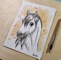 a drawing of a horse on a table next to a pencil and watercolor paper