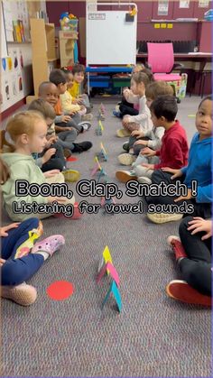 a group of children sitting on the floor playing with toy boats and paper airplanes in a classroom