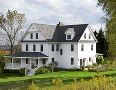 a large white house sitting on top of a lush green field