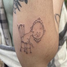 a person with a tattoo on their leg that has a drawing of a dog sitting in a chair