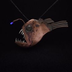 a metal fish with its mouth open on a black background