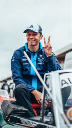 a man sitting on top of a motorcycle giving the peace sign in front of him