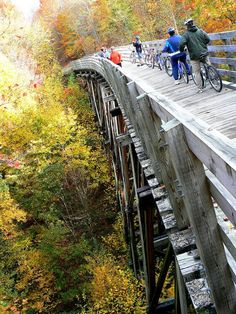 several people riding bikes on a wooden bridge