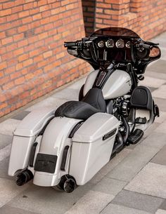 a white and black motorcycle parked next to a brick wall