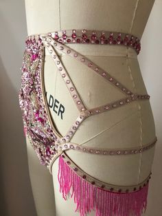 a mannequin with pink beads and fringes on it's back, in front of a white wall