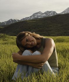 a woman sitting in the grass with her arms crossed