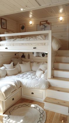 a bunk bed with white pillows is in the middle of a room that has stairs leading up to it