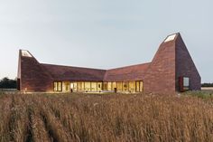 a house with two triangular shaped windows in the middle of tall grass and brown grasses