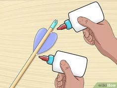 two hands holding paint cans and an arrow on a wooden surface with the tip of a brush