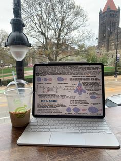 an open laptop computer sitting on top of a wooden table next to a cup of coffee