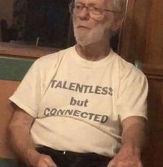 an older man sitting on a bench wearing a t - shirt that says talented but connected