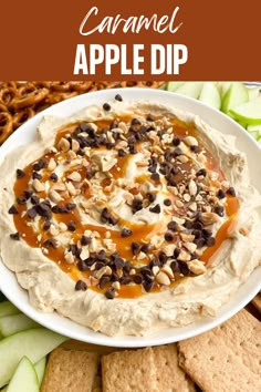 caramel apple dip in a white bowl surrounded by crackers and pretzels