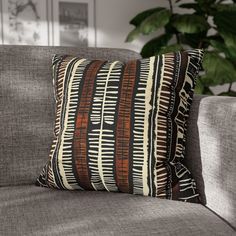 a close up of a pillow on a couch near a potted plant in a living room