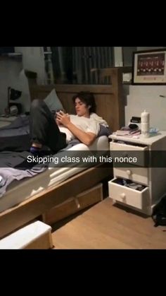 a man laying on top of a bed next to a wooden desk and computer monitor