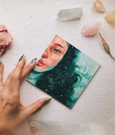 a woman's hand is holding a piece of art